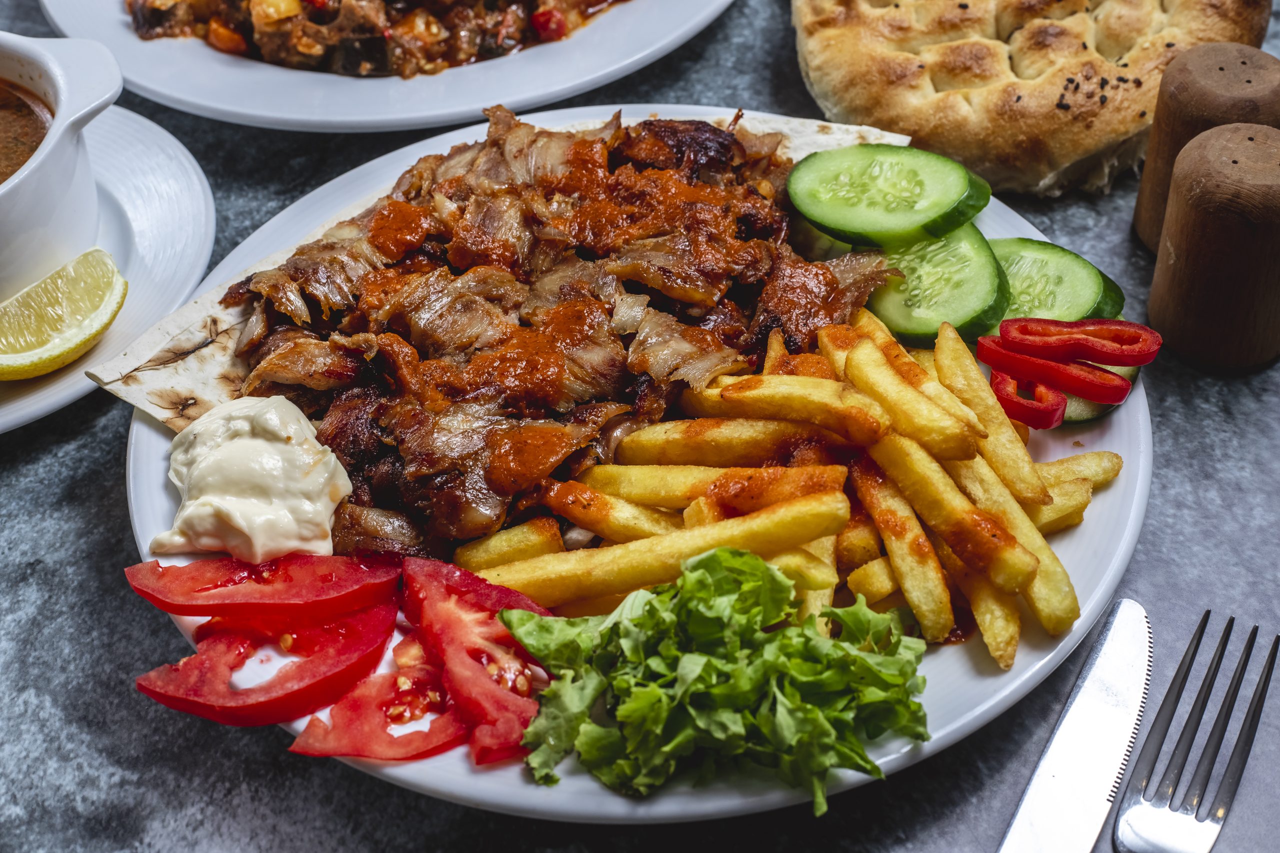 side view doner plate with french fries tomato fresh cucumber yogurt bread table scaled